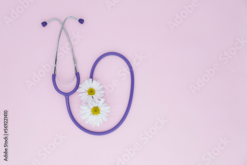 Stethoscope, white flower on pink background with copy space. Medical flat lay. International Nurse's Day. Women's Day. March 8th