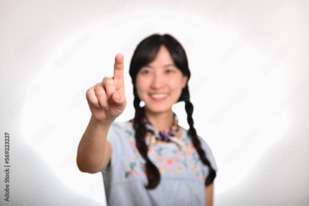 Portrait of beautiful happy young asian woman in denim dress touching invisible screen on white background. Portrait of beautiful happy young asian woman in denim dress touching invisible screen on white background.