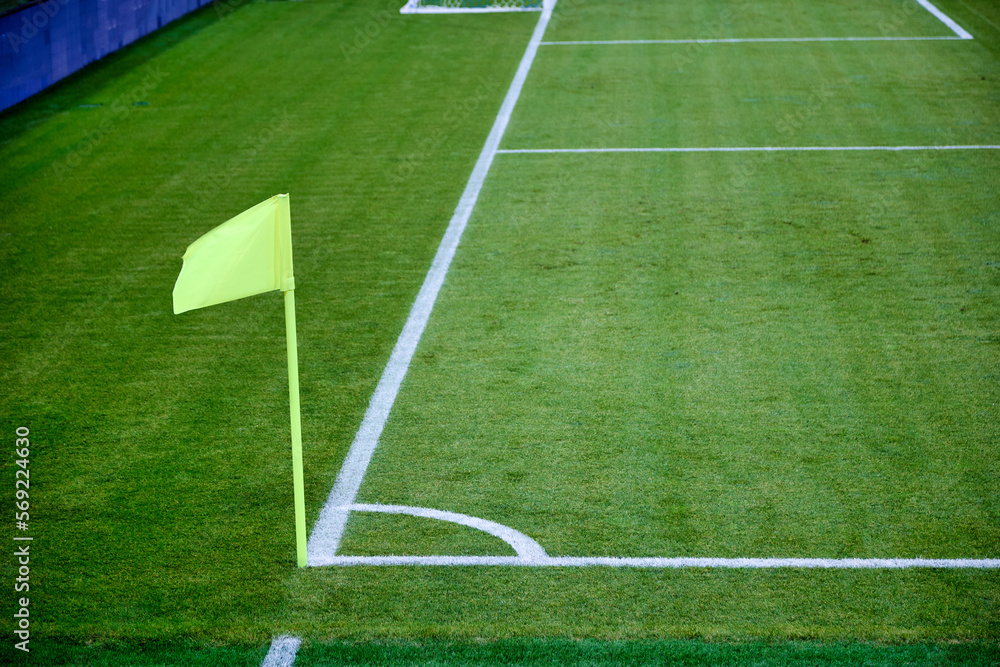 Obraz premium On right corner of the football field there is a green flag on the flagpole. Corner flag as a special element of marking is used by the referee of the match on football with insufficient visibility