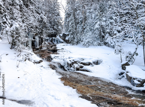 A gentle stream running through a snowy winter landscape in the mountains of New Hampshire Franconia Ridge Mt. Lafayette. photo