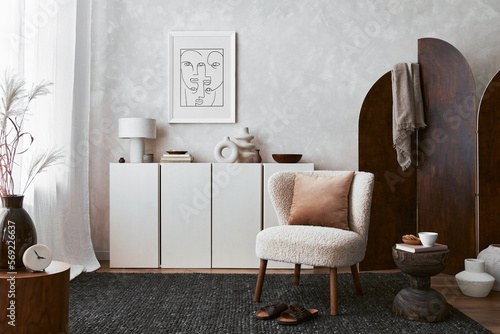Foto Stylish composition of cozy living room interior design with mock up poster frame, fluffy armchair, folding screen, coffee table, commode and personal accessories