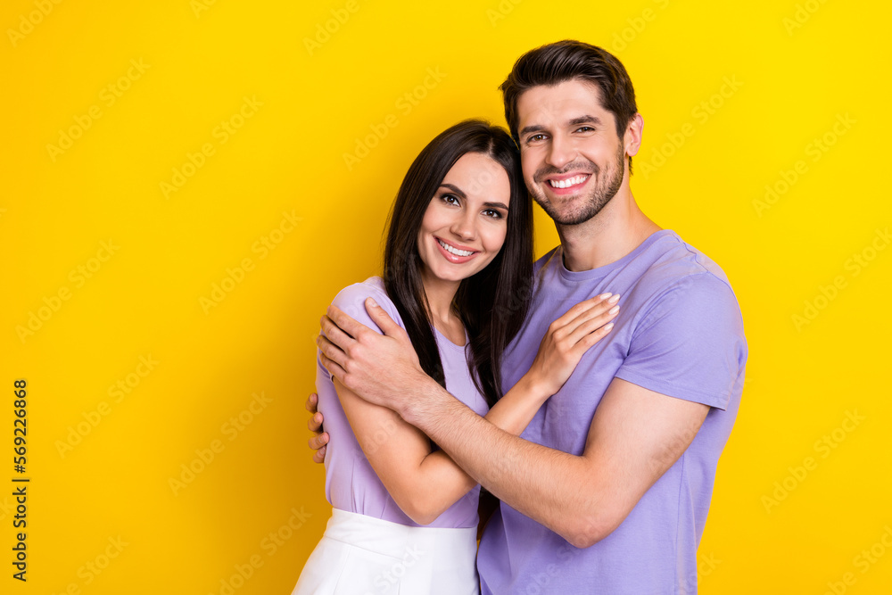 Photo of idyllic peaceful positive partners hug toothy smile empty space isolated on yellow color background Photo of idyllic peaceful positive partners hug toothy smile empty space isolated on yellow color background