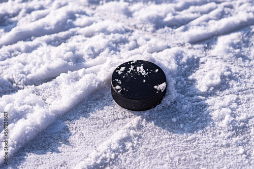 Photography hockey puck lies on the snow close-up