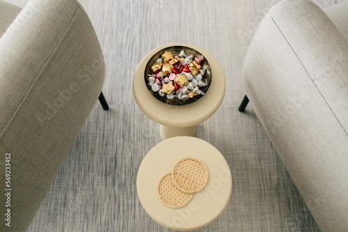 bowl of chocolate candy wrapped in foil on small table between two chairs in waiting room photo