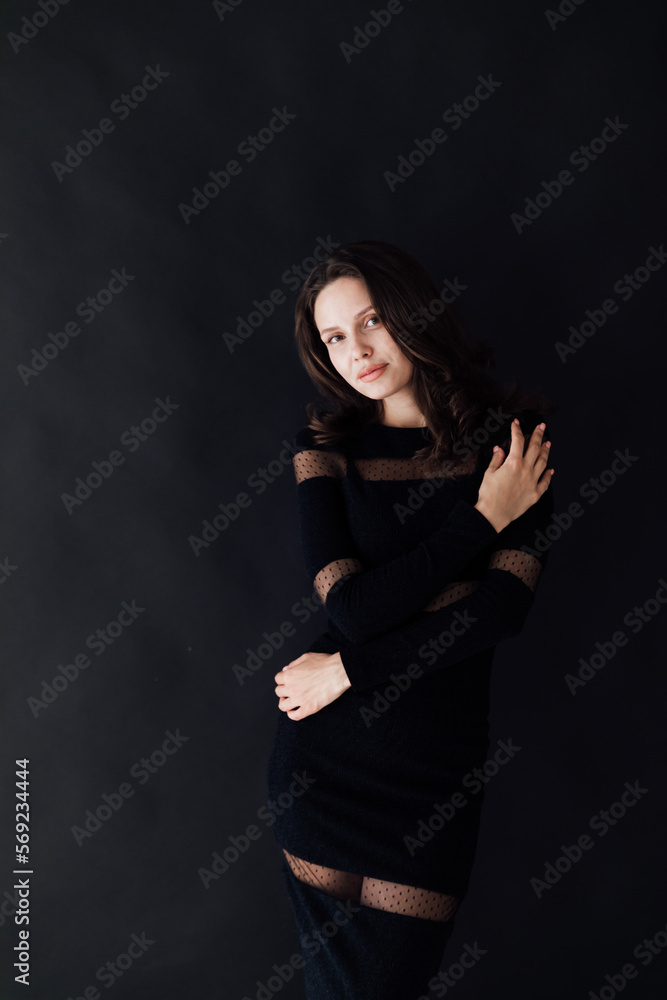 brunette in a dark dress poses on a dark background brunette in a dark dress poses on a dark background