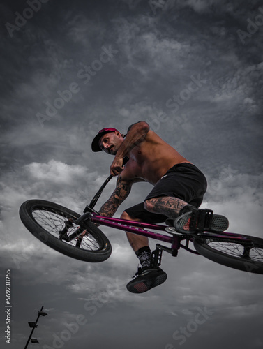 Bmx rider in the skatepark jumping with the bike. Boy with tattoos. Urban photography