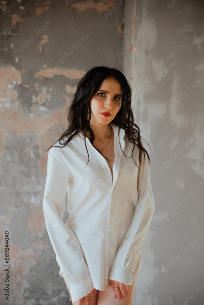 Sexy young brunette girl in a white shirt and lingerie in a loft photo studio Sexy young brunette girl in a white shirt and lingerie in a loft photo studio