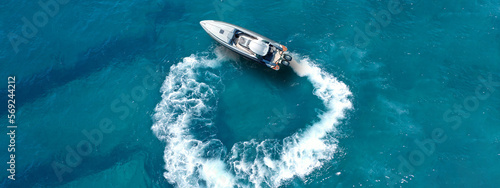 Aerial drone top down ultra wide photo with copy space of inflatable power rib boat making extreme manoeuvres in Mediterranean bay with deep blue sea at dusk