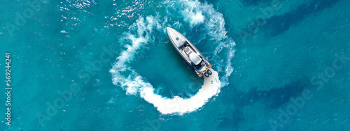 Aerial drone top down ultra wide photo with copy space of inflatable power rib boat making extreme manoeuvres in Mediterranean bay with deep blue sea at dusk