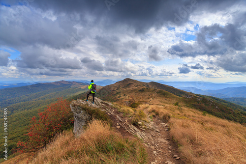female tourist in a green jacket on a rock in the mountains