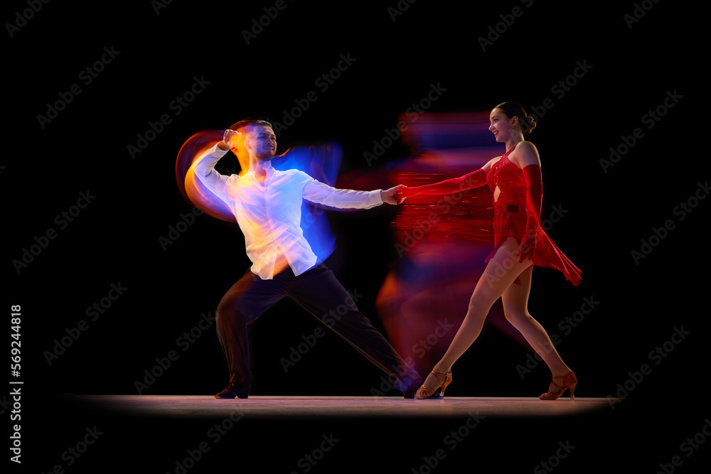 Talent. Beautiful young people, man and woman dancing tango, ballroom over black background with mixed neon lights. Concept of hobby, lifestyle, action, beauty of movements, emotions, fashion, art