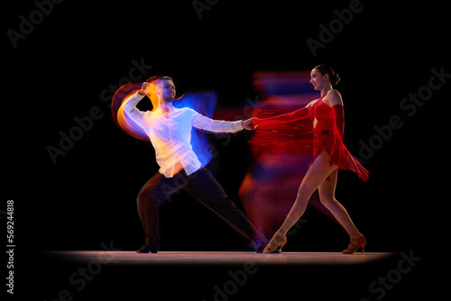 Talent. Beautiful young people, man and woman dancing tango, ballroom over black background with mixed neon lights. Concept of hobby, lifestyle, action, beauty of movements, emotions, fashion, art
