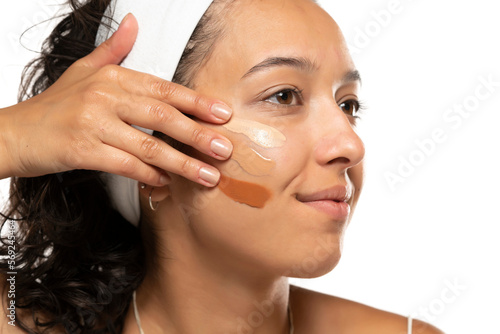 Face of dark skinned woman with tree different tones of liquid foundation on a white background