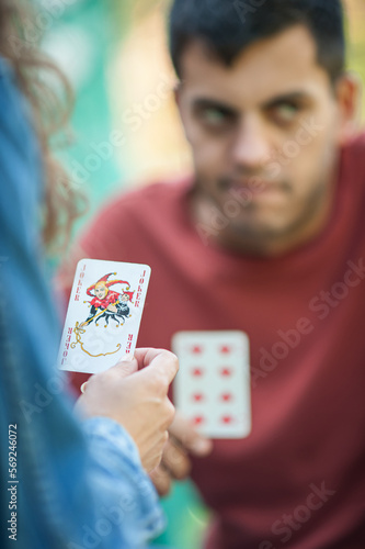 Playing cards in the spring garden. A woman plays cards and holds a joker in her hand.