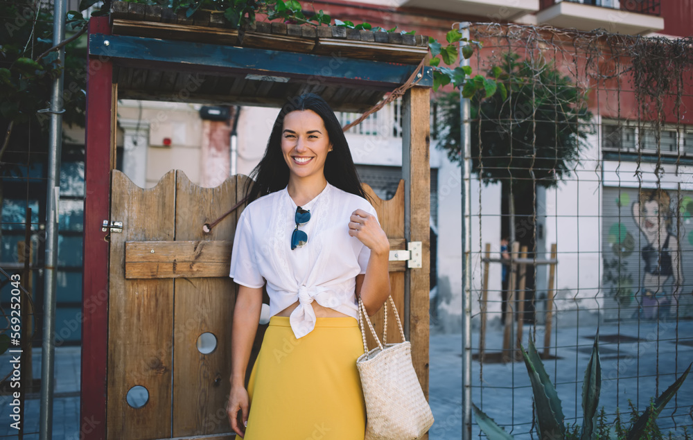 Half length portrait of joyful female tourist in stylish outfit smiling at camera during positive day spending in travel city, cheerful Caucasian woman in yellow skirt enjoying pastime and rejoicing Half length portrait of joyful female tourist in stylish outfit smiling at camera during positive day spending in travel city, cheerful Caucasian woman in yellow skirt enjoying pastime and rejoicing