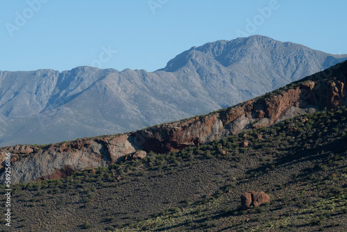 Принти на полотні Red stone hill dwarfed by the imposing Swartberg mountains near De Rust, Western Cape
