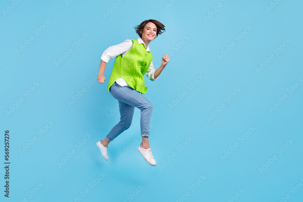 Full size photo of pleasant gorgeous girl brown hairdo wear green vest jeans running at sale shopping isolated on blue color background Full size photo of pleasant gorgeous girl brown hairdo wear green vest jeans running at sale shopping isolated on blue color background