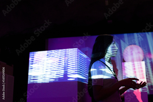 Side view of businesswoman gesturing by projection screen in illuminated convention center