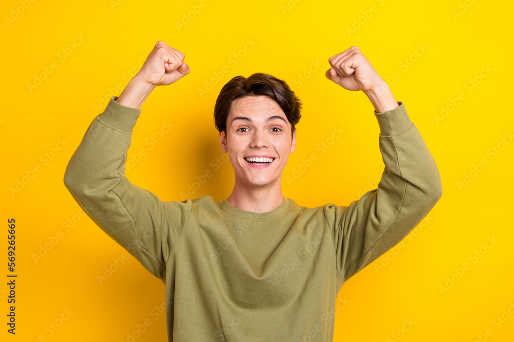 Portrait of delighted cheerful person beaming smile raise fists luck isolated on yellow color background Portrait of delighted cheerful person beaming smile raise fists luck isolated on yellow color background