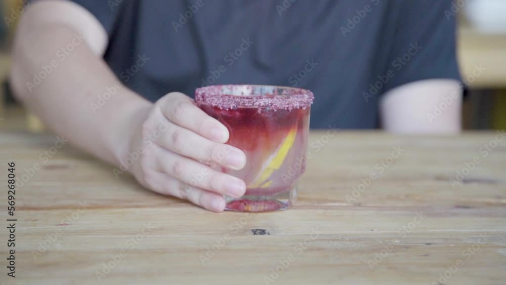 Mezcal con hielos, limón y granada en un vaso escarchado con sal.	