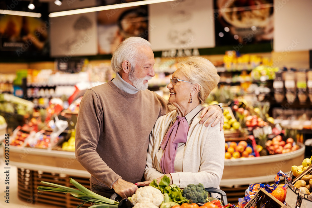 A happy senior couple is hugging at the supermarket while shopping. A happy senior couple is hugging at the supermarket while shopping.