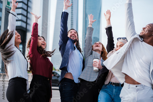 Group of business people putting their hands together and celebrating the successes of the company while taking a break in the street. Concept: finance, business, skyline