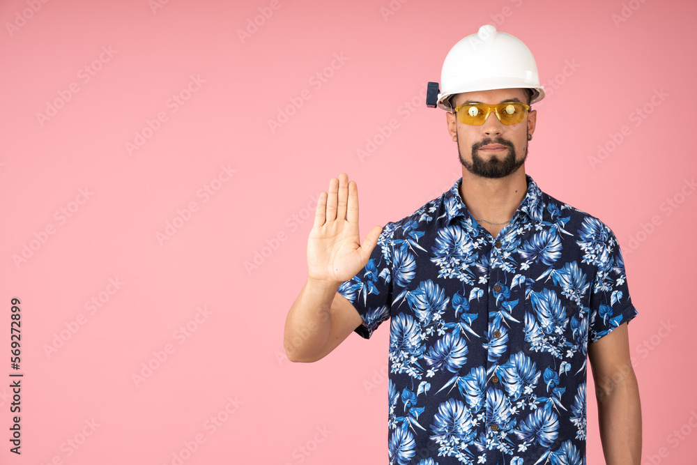 Serious man wearing a helmet and signaling to stop with his hand