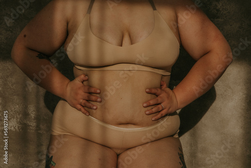 close up of plus size filipino woman with hands on stomach