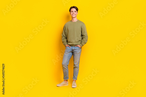 Full length photo of cheerful glad man wear comfort fashionable khaki outfit promoting new collection isolated on yellow color background