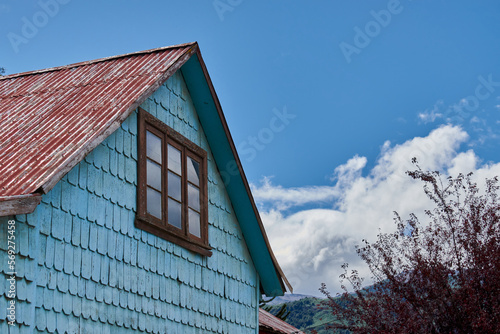 Old wooden blue house with a red weathered tin roof