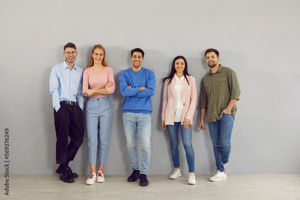 © Studio Romantic - Confident toung team. Portrait of group of different positive smart young people on gray wall background. Men and women in stylish smart and casual clothes stand in row and smile looking at camera. © Studio Romantic - Confident toung team. Portrait of group of different positive smart young people on gray wall background. Men and women in stylish smart and casual clothes stand in row and smile looking at camera.