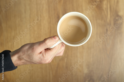 white mug with coffee held in hand