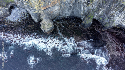 vista aerea de un mar enfurecido con grandes olas rompiendo en las rocas de un acantilado photo