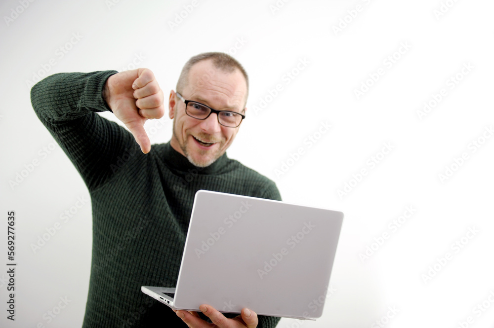 adult man in glasses with laptop on white background shows thumbs down he is pleased he beat someone outperformed in competition won turned out to be worse satisfied office concept of victory