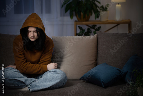 sad teenager girl sitting on couch indoor at night © Maya Kruchancova