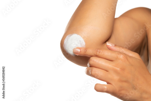 Close up of a  woman takes care of her elbows using cosmetic cream on a white studio background