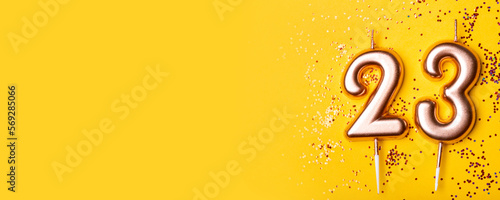 23 years celebration. Greeting banner. Gold candles in the form of number twenty three on yellow background with confetti.
