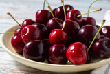 Close-up of fresh sweet cherries on a yellow plate on a wooden background.