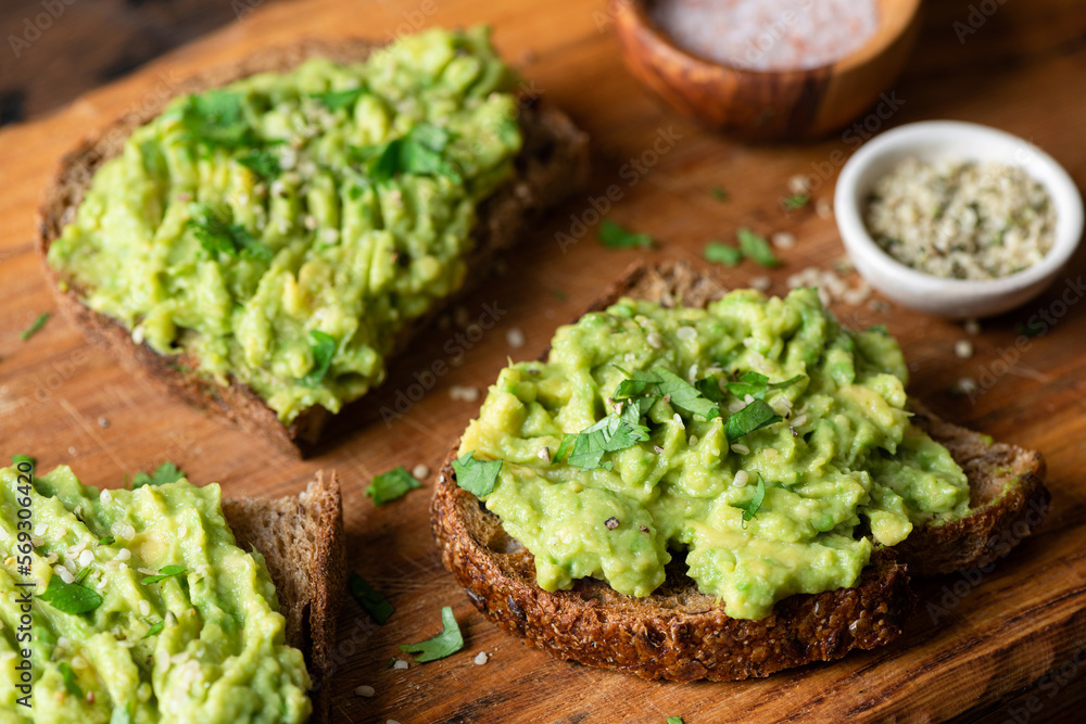 Vegan avocado toast with cilantro and hemp seeds on a wooden background, closeup view. Healthy snack Vegan avocado toast with cilantro and hemp seeds on a wooden background, closeup view. Healthy snack