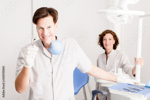 Dentists portrait. Mature professional man and woman in uniform standing in dentist office looking at camera 