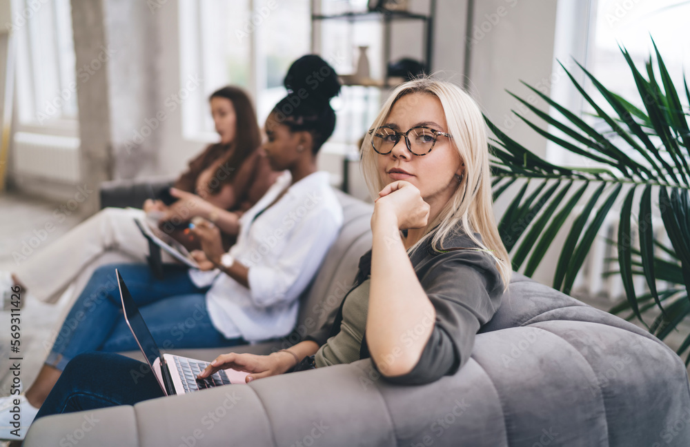 Multinational women sitting with gadgets on sofa Multinational women sitting with gadgets on sofa