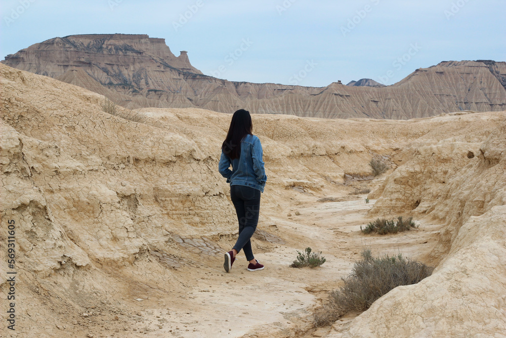 Woman walking through a desert landscape