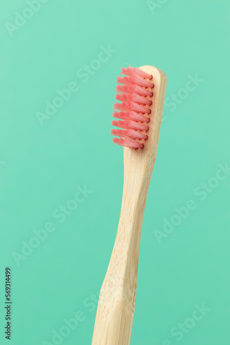 Bamboo toothbrush with pink bristles on blue background. Close up.