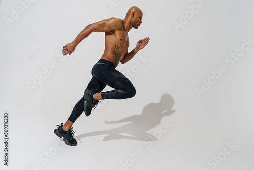Professional male athlete running isolated on white studio background with shadows