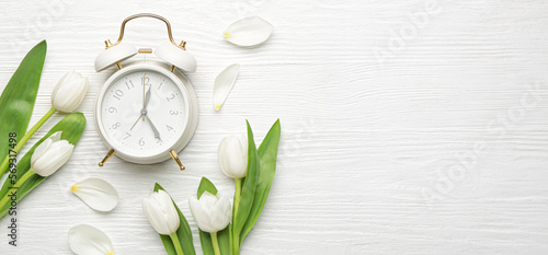 Fotografija Banner with alarm clock and tulips on white wooden background