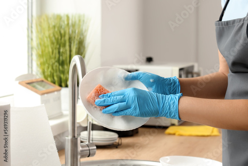 Female janitor washing plate in kitchen, closeup