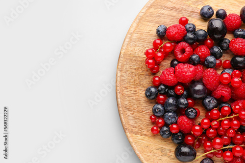 Wooden board of fresh berries on color background, closeup