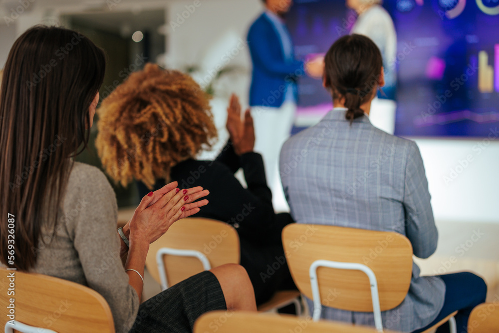 Audience clapping at conference.