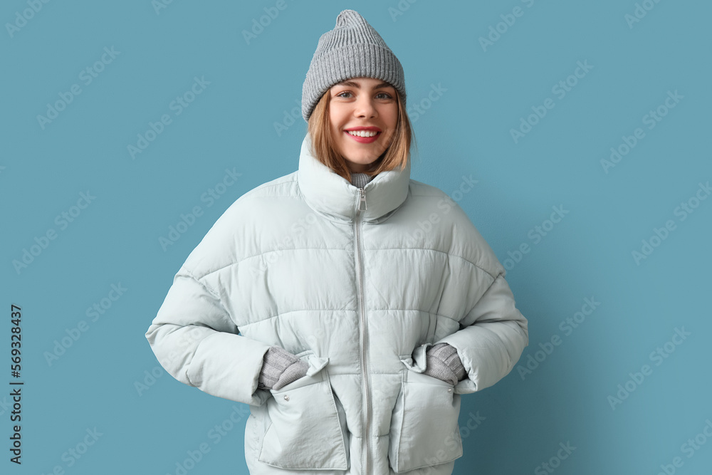 Frozen young woman in winter clothes on blue background Frozen young woman in winter clothes on blue background