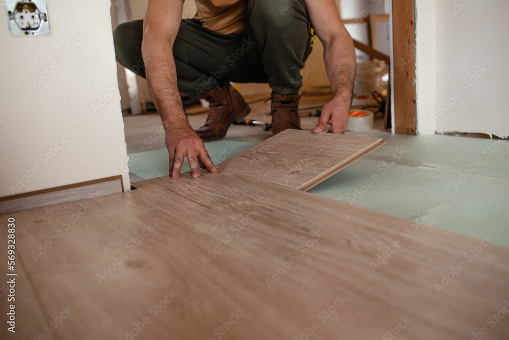 The man is putting laminate in the room at the home
